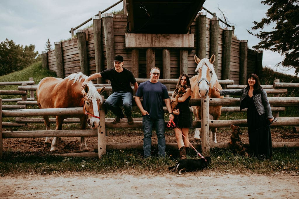 A man and two women standing next to horses.